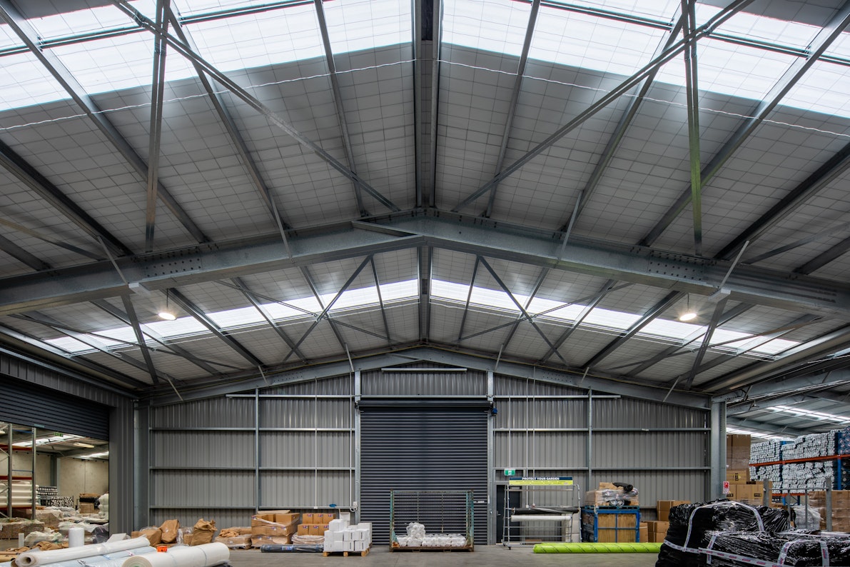 The interior of an industrial storage warehouse features exposed steel framing and a roller door at the end.